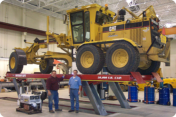 Road grader on lift in shop